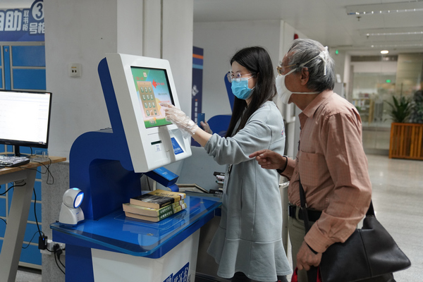2.馆员(左)引导读者使用自助借还设备.JPG